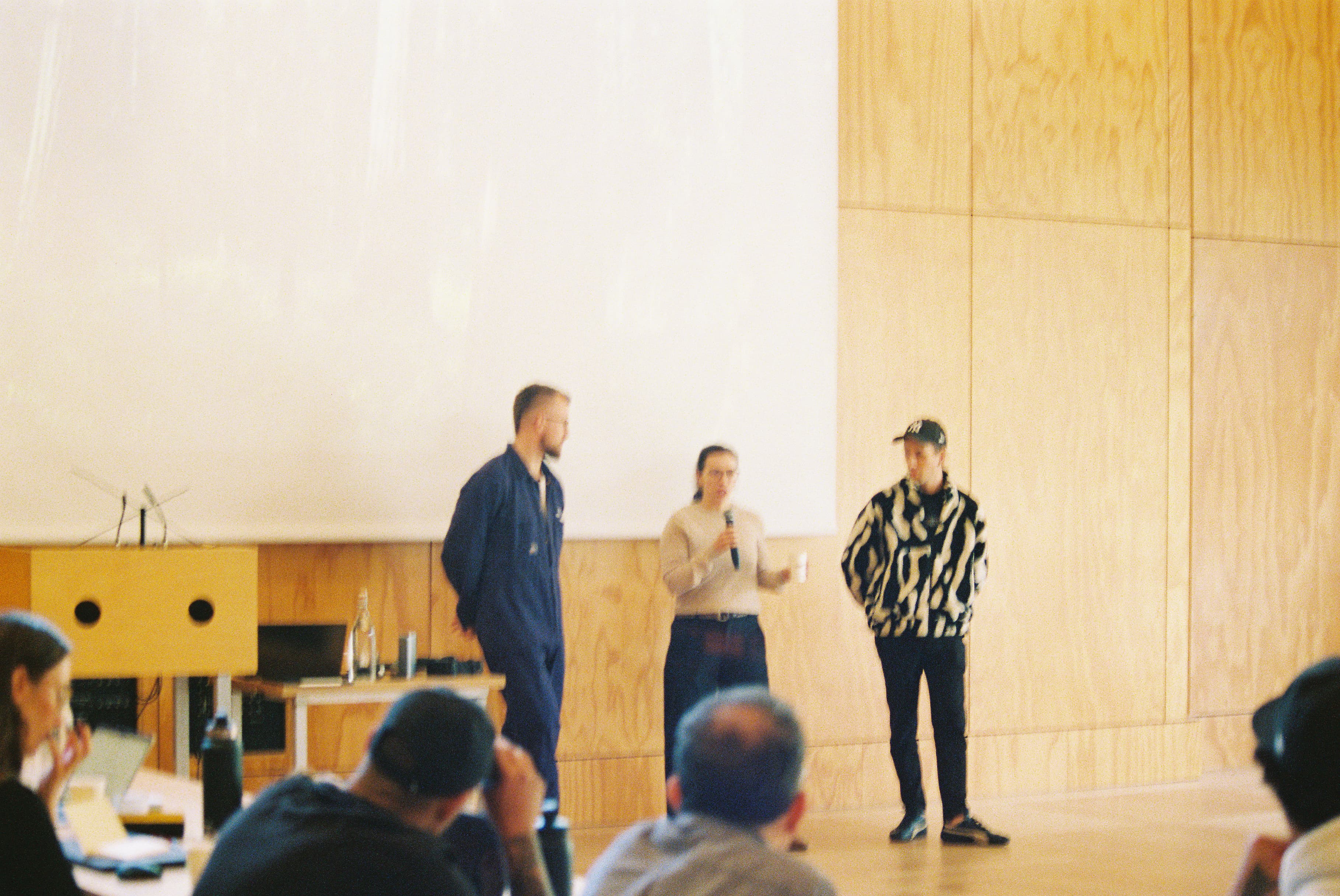 Three builders at the front of the room, mid-presentation